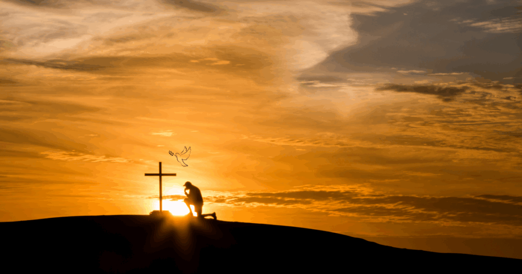 Silhouette of a man kneeling at a cross on a hill at sunset with a dove in the sky, symbolizing faith, prayer, and peace.